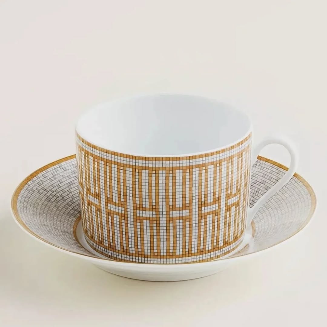 The Hermes Mosaique au 24 gold breakfast cup and saucer set of 2 features a luxurious and elegant design by the renowned brand, HERMES.